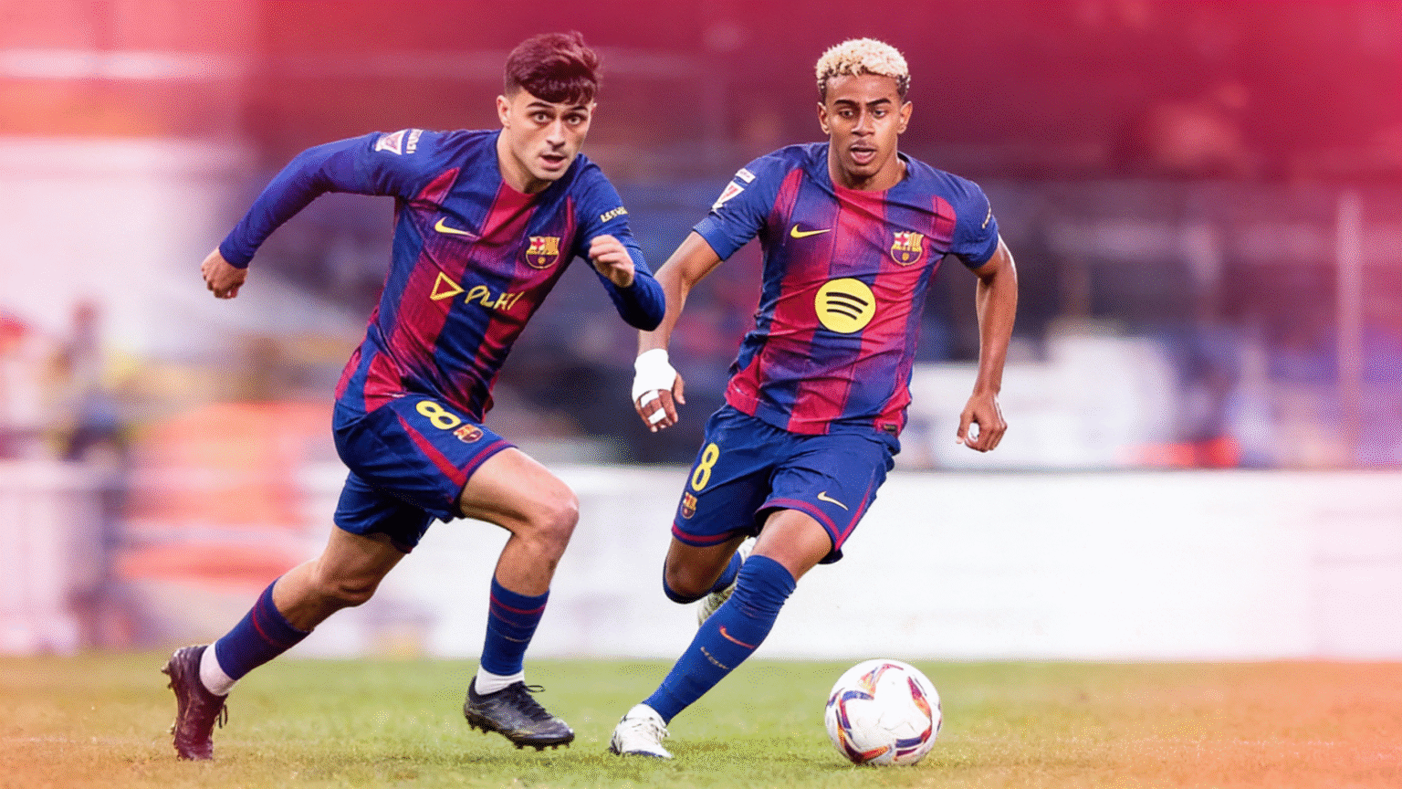 Two young midfield and winger players wearing Barcelona style jerseys during a match